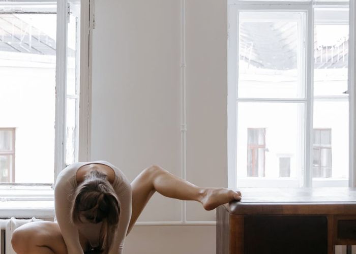 Person performing a balance yoga pose in a minimal room